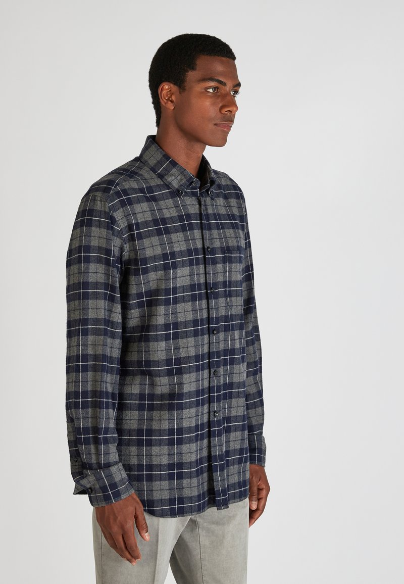 Camisa de cuadros en navy y gris con botones, confeccionada en una tela suave, con un collar clásico, mangas largas y un bolsillo en el pecho.