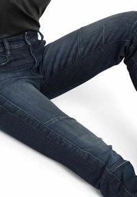 Tumedat sinised teksapüksid slim fit lõikega, millel on peen hajumine, detailne õmblusmustrite disain ja kõrge vöökoht.