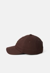 Casquette de baseball en coton marron avec une visière courbée, six œillets d'aération et un petit logo à l'avant. Construction et ajustement classiques.