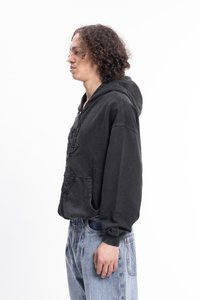 Un hoodie noir avec un design texturé et des poches avant, associé à un jean bleu clair. Le tissu semble doux, avec une coupe décontractée et une capuche à cordon.