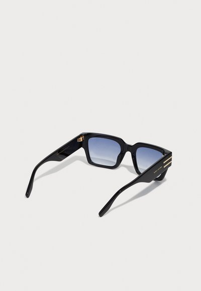 Gafas de sol de plástico negro con montura cuadrada, lentes degradados en azul, detalles dorados en las patillas y un acabado brillante.