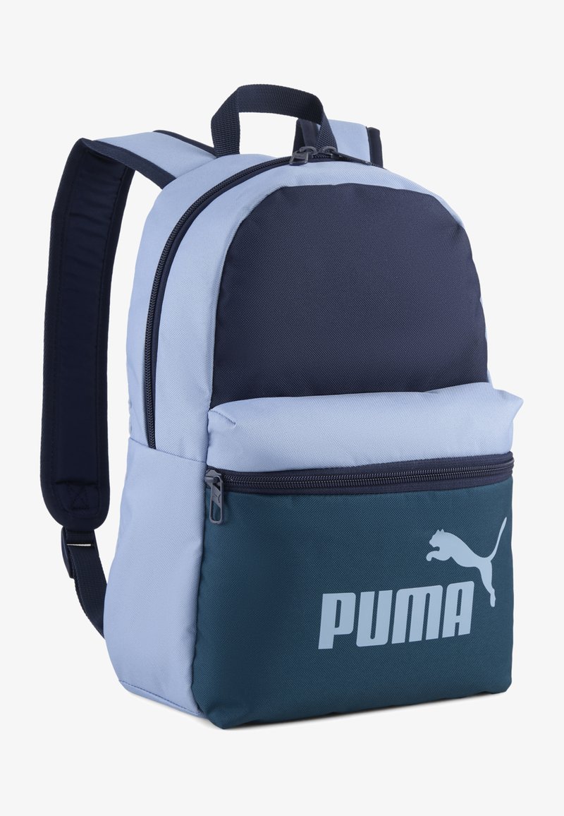 Μπλε και ναυτικό σακίδιο πλάτης Puma με μαλακούς ιμάντες, μπροστινή τσέπη με φερμουάρ, πάνω χερούλι και λογότυπο Puma στο κάτω μπροστινό τσεπάκι.