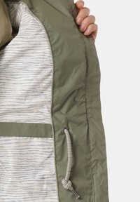 Giacca verde oliva con un esterno testurizzato, dotata di una fodera beige a righe, due tasche e dettaglio con cordoncino all'orlo.