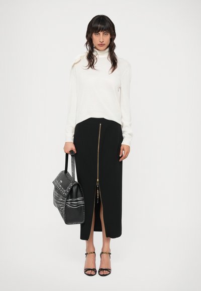 Suéter branco de gola alta, saia midi preta com fecho na frente, bolsa preta com detalhes em padrões e saltos pretos com tiras.