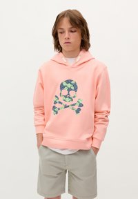 Felpa rosa chiaro in morbido materiale con design di teschio e ossa incrociate in un motivo di foglie blu e verdi. Cavetti in colore a contrasto.