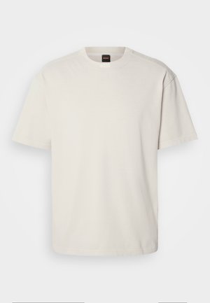 Krátký rukáv, tričko s kulatým výstřihem v off-white bavlně, s rovnými liniemi a minimálním brandingem na límci. Měkká textura, bez vzorů.