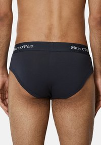 ciemnoniebieskie męskie slipy wykonane z miękkiego materiału, o gładkim wzorze, z elastycznym paskiem w bieli z logo "Marc O'Polo".