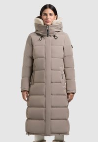 Garšs, pildīts mētelis gaiši bežā krāsā ar augstu apkakli un mākslīgās kažokādas oderi. Iekļauj rāvējslēdzēja priekšu, regulējamas pievilkšanas cilpas un sānu kabatas.