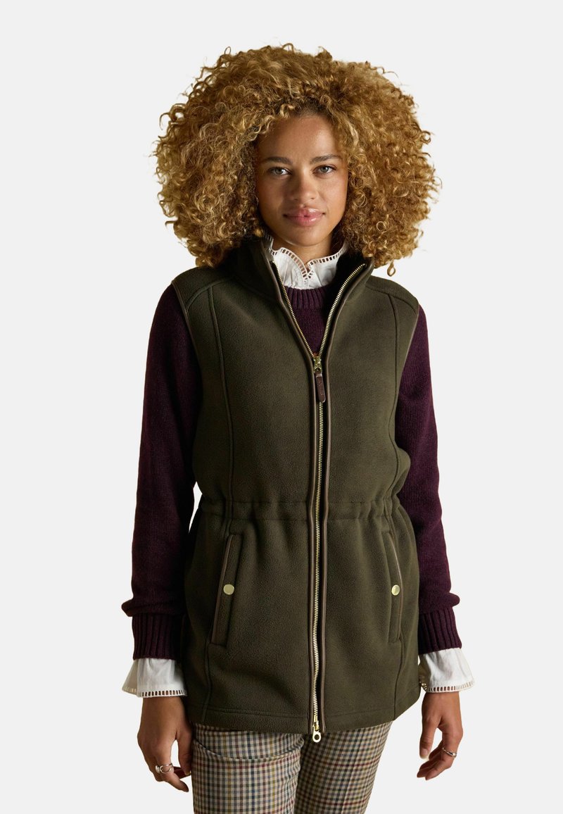 Olívovo zelená fleece vesta so zipsom vpredu, bočnými vreckami, s tunelovou šnúrkou v páse a vysokým golierom, prekrytá burgundským sveterom a vzorovanými nohavicami.
