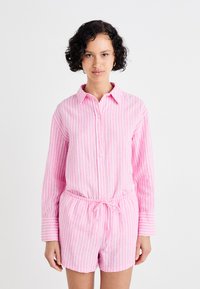 Conjunto de camisa riscada em rosa e calções feito de tecido leve, apresentando botões, um colarinho e uma cintura elástica com detalhe de cordão.