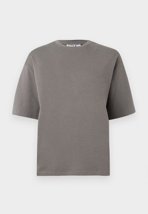 Maglietta a maniche corte con scollo tondo, semplice, di colore grigio-marrone tenue, mostrata distesa su uno sfondo chiaro.