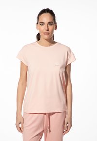 Lichtroze katoenen T-shirt met korte mouwen, ronde hals en een klein geborduurd logo op de voorkant. Zachte textuur en een ontspannen pasvorm.