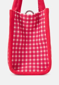 Sac fourre-tout rouge avec un motif à carreaux présentant des lignes blanches. Fabriqué en tissu tissé avec une finition texturée. Comprend un anneau en argent en haut.