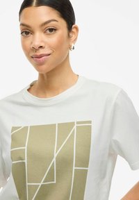 Vit t-shirt med en geometrisk guld grafisk design framtill. Korta ärmar och en rund halsringning kompletterar den lediga stilen.