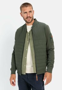 Groene bomberjack met een gewatteerde voorkant, geribde manchetten en een rits. Heeft een lichtgroene binnenlaag en een verstelbare zoom.