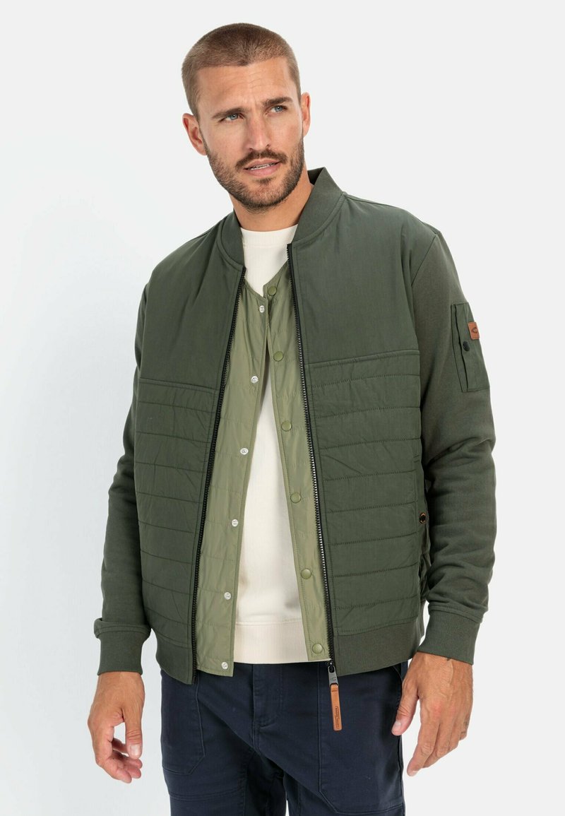 Groene bomberjack met een gewatteerde voorkant, geribde manchetten en een rits. Heeft een lichtgroene binnenlaag en een verstelbare zoom.