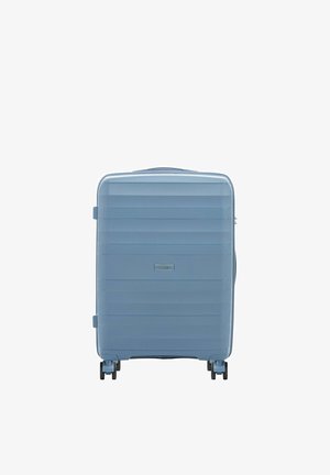 Niebieska walizka z twardą skorupą na czterech kółkach, z poziomymi żebrowaniami i centralną metką marki na przednim panelu.