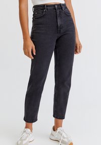 Jeans negros de talle alto hechos de denim; ajustados en la cintura, corte recto, diseño de cinco bolsillos, textura sutilmente desgastada.