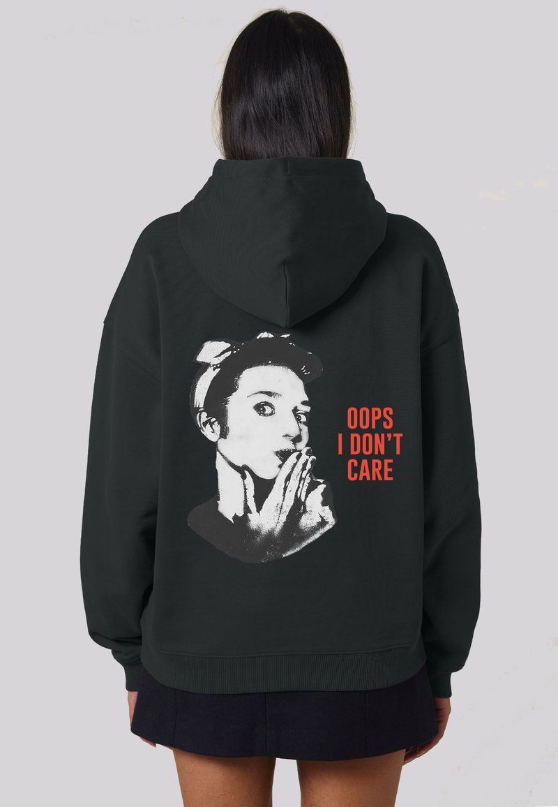 Sudadera negra con un estampado gráfico de una persona con una mano en la boca y el texto "OOPS I DON'T CARE" en rojo. Tejido suave, corte relajado.