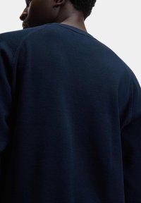 Maglione in maglia con texture blu navy, dal collo tondo e dal taglio morbido, caratterizzato da un delicato motivo a coste e cuciture standard sulle spalle.