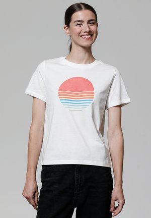 T-shirt en coton blanc avec un graphisme de coucher de soleil corail rond et des rayures colorées en bleu et vert. Manches courtes et design col ras du cou.