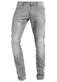 Vaqueros de mezclilla gris con un ajuste entallado, cinco bolsillos y un descolorido sutil en las piernas. Presentan un botón metálico y cierre de cremallera.