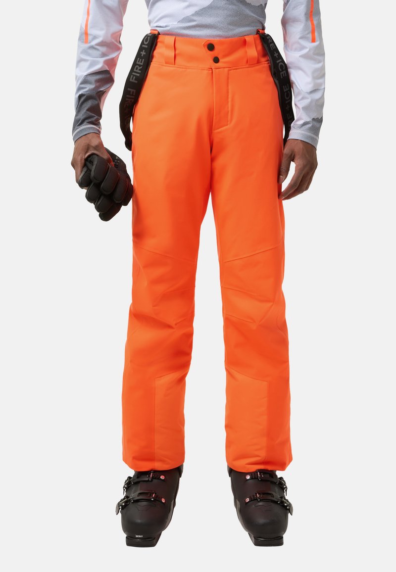 Jasnopomarańczowe spodnie narciarskie wykonane z trwałego, odpornego na warunki atmosferyczne materiału. Cechy to regulowane szelki, boczne kieszenie oraz wyraźne szwy.