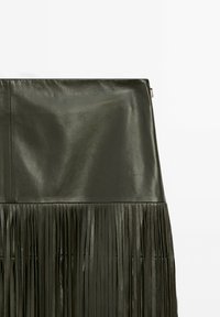 Ciemnozielona skórzana spódnica z gładką górną częścią i teksturowanym frędzlem na dole. Czysty design z nowoczesnym wykończeniem.