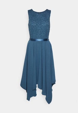 Robe bleue sans manches avec corsage en dentelle, ceinture en satin à la taille et jupe fluide asymétrique sur fond uni.