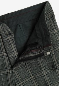 Pantalones de cuadros con un patrón en gris oscuro y negro. Tejido de algodón, con un botón formal y una cremallera, y con un forro interior suave.