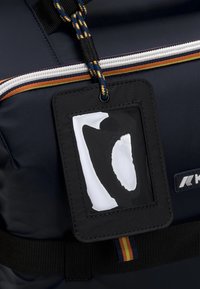 Zaino blu navy con una grande cerniera e accenti a strisce colorate. Presenta un portadocumenti nero con una finestra trasparente per esporre le carte.
