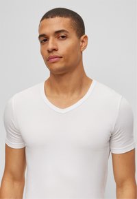 White, short-sleeve, stretch cotton V-neck t-shirt with a fitted design, smooth texture, and minimal stitching details.