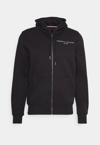 Felpa nera con zip realizzata in tessuto morbido, dotata di tasca frontale, cappuccio con cordino e logo ricamato sul petto. Presenta polsini a coste.