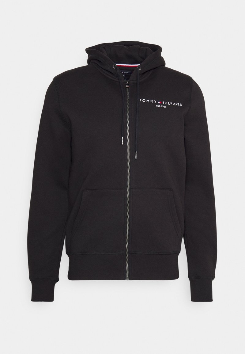 Felpa nera con zip realizzata in tessuto morbido, dotata di tasca frontale, cappuccio con cordino e logo ricamato sul petto. Presenta polsini a coste.