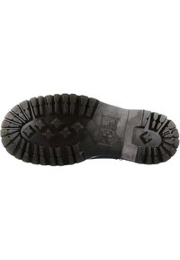 Semelle en caoutchouc noir avec un motif de crampons profond, comportant des lugs rectangulaires et en forme d'étoile pour l'adhérence. Finition lisse avec une étiquette en relief.