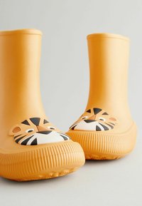Bottes de pluie en caoutchouc orange avec un design de visage de tigre sur le devant, avec des rayures noires et un bout arrondi, accentuées par une semelle texturée.