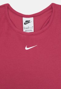 Burgundas ribota bezšuvju topiņš ar apaļu kaklu, ar mazu balto Nike swoosh logo. Etiķete norāda izmēru M, ražots Vjetnamā.