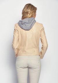 Ljusbeige läderjacka med grå huva, skräddarsydd design, sydda detaljer och midjeband med diskreta fickor.