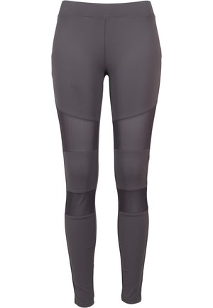 Szürke leggings, amelyet illeszkedő kialakítás jellemez, átlátszó betétekkel az alsó lábszáron. Simító szintetikus anyagból készült.