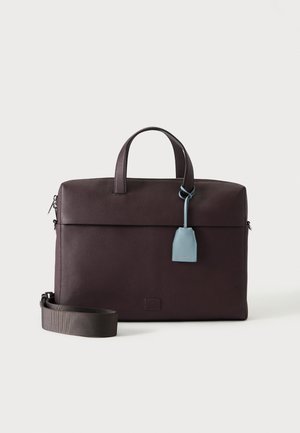 Serviette en cuir marron foncé avec poignées supérieures, bandoulière amovible et étiquette en cuir bleu clair suspendue à une poignée.