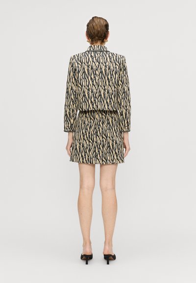 Beige tooniku ja mini seeliku komplekt musta abstraktse disainiga; sile tekstuur; slim-fit siluett; lühikesed varrukad ja kõrge kaelus.
