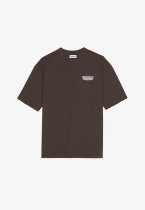 Barna pamut póló laza fazonnal, rövid ujjakkal, és egy kis "ÍZLETES FRISS GYÜMÖLCS" grafika fehér és lila színekben.