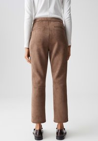 Pantaloni in suede marrone con una texture liscia, vita media, e un design elegante, dotati di tasca posteriore e gamba cropped.