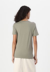 Olive green t-shirt with short sleeves, round neckline, and a relaxed fit. Made from soft cotton fabric, features a smooth texture.