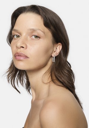 Silberne Ohrhänger mit rechteckigem Design, das eine polierte Oberfläche und subtile geometrische Akzente aufweist. Die glatte Textur unterstreicht die Eleganz.