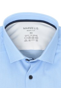 Helles blau kariertes Hemd mit Knopfkragen, ausgestattet mit einem schwarzen Knopf sowie Etiketten für Größe und Pflegehinweise im Inneren.