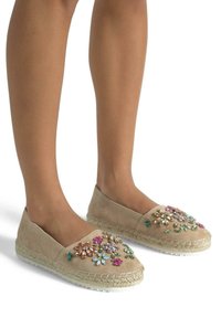 Beige suède espadrilles met bloemenversieringen in roze, groen en goud, met jute touwzolen en een ronde neus.