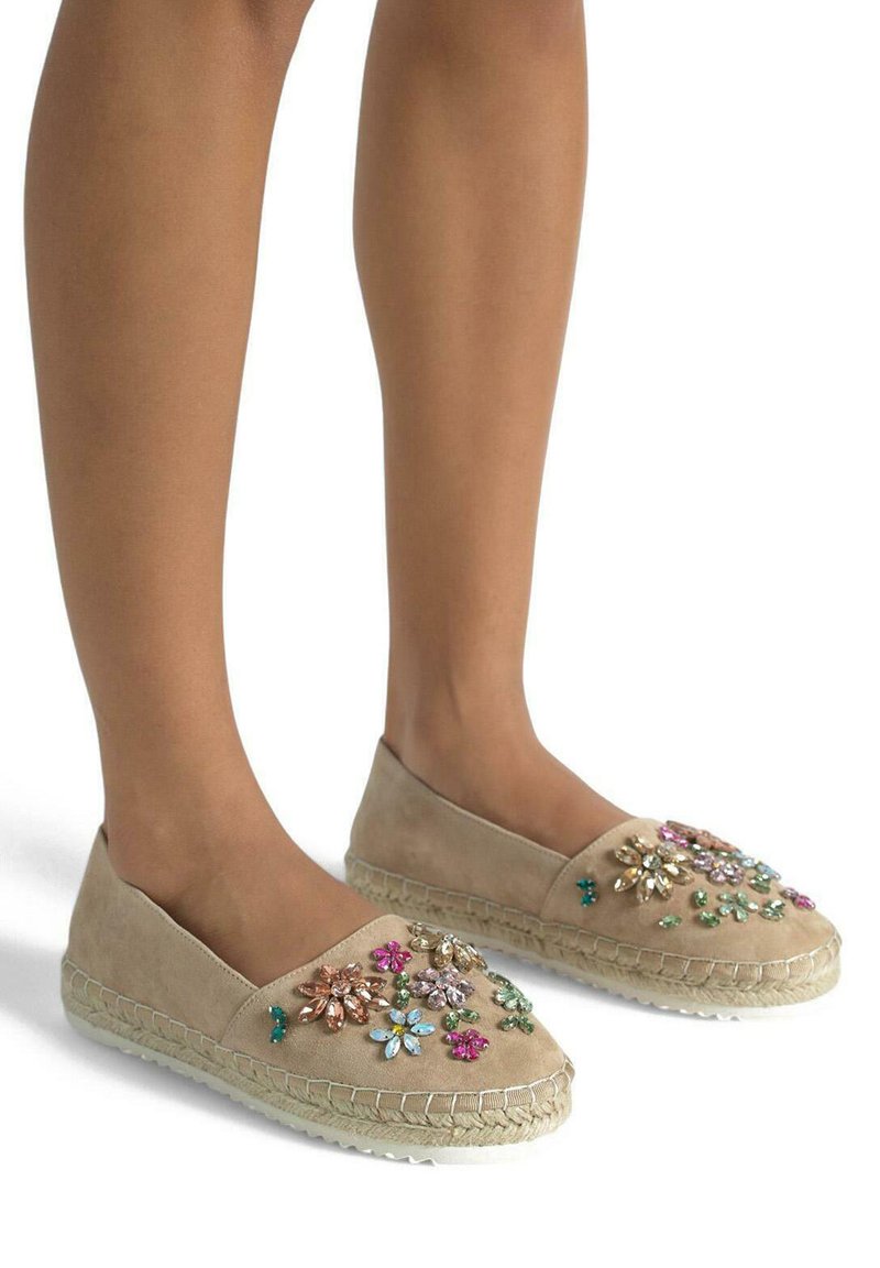 Beige suède espadrilles met bloemenversieringen in roze, groen en goud, met jute touwzolen en een ronde neus.