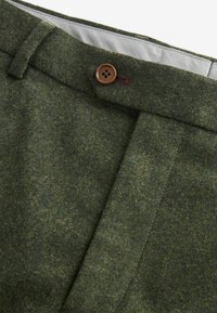 Pantalons en mélange de laine verts avec une texture lisse, une fermeture à bouton marron et une coupe classique avec des détails de couture soignés.