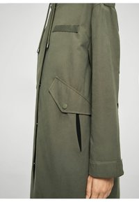 Manteau vert olive avec une texture lisse, doté d'une poche latérale, d'une fermeture à boutons et d'une capuche avec cordon de serrage. Design simple avec un minimum de détails.